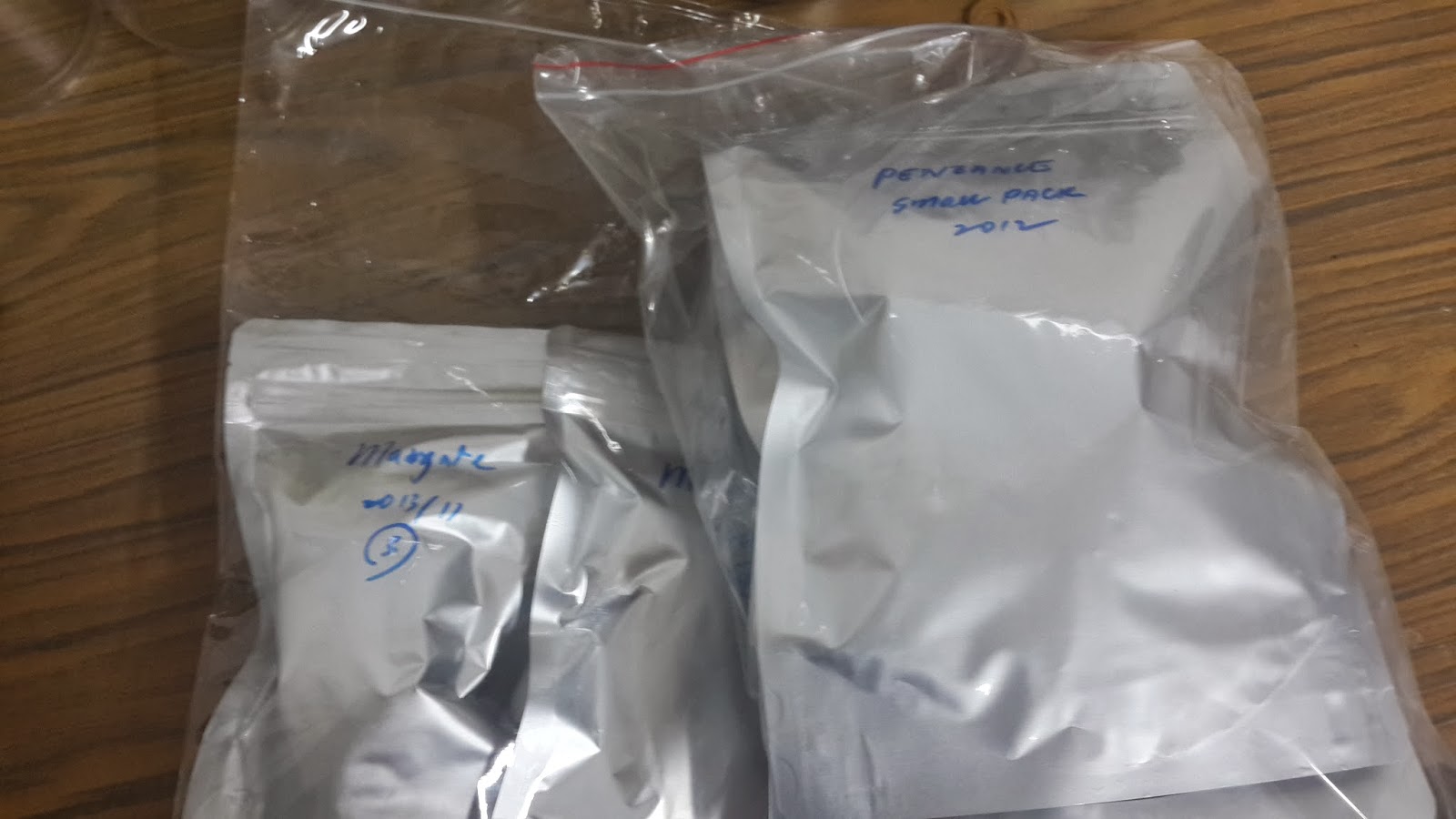 数袋带有手写标签的银色热封袋，外面套着透明袋